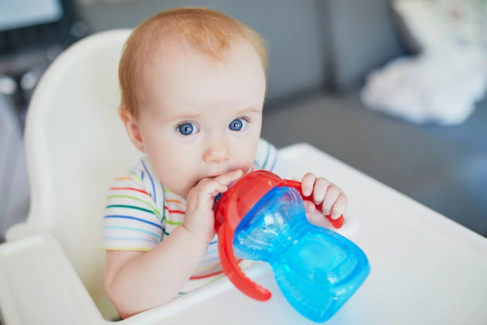 bébé boit de l'eau à la tasse